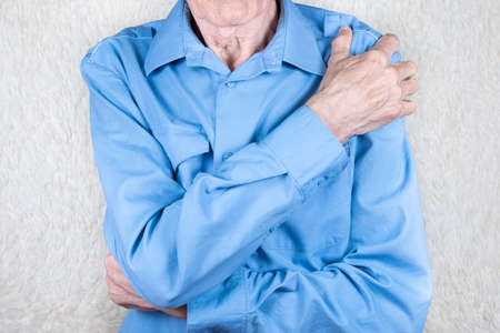 Male hand holding shoulder. Eldery man suffering from pain in brachium. Bone disease. White background.の写真素材