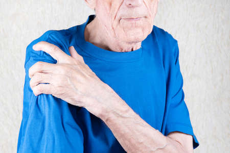 Eldery man suffering from pain in brachium. Male hand holding shoulder. Bone disease. White...