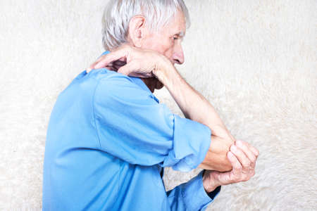 Male hands holding elbow. Old man suffering from pain in bones. White background