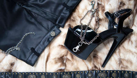 Fashion collage with chain, belt, female black high-heeled strips shoes on fur background.の写真素材