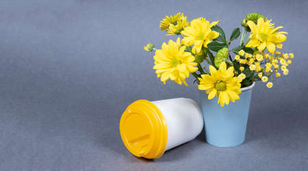 Bouquet of yellow flowers and paper coffee cup on gray background. Copy spaceの写真素材