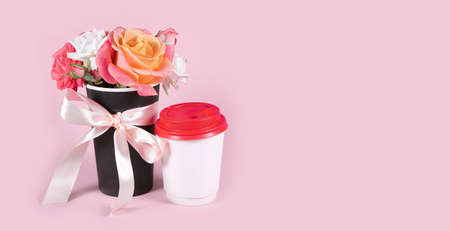 Bouquet of rose flowers and paper coffee cup on pink background. Copy space