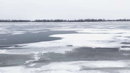 Snow river winter landscape. Frozen ice and snow by river. Spring thawed ice on water.の写真素材