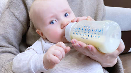 Little kid drinking milk from bottle. Cropped view of mother hand. infant foodの写真素材