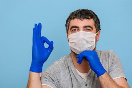 A man in a medical mask and blue medical gloves.の写真素材