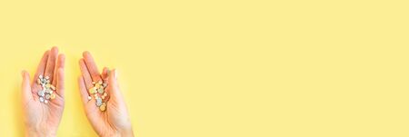 Medical pills in womens hands. Hands holding medicine on a yellow background.の写真素材