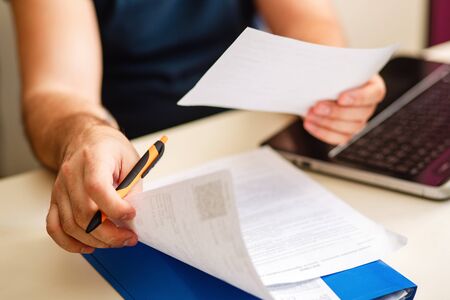 Documents in mens hands. Remote work. A man at a Desk with documents works online. Home environment.