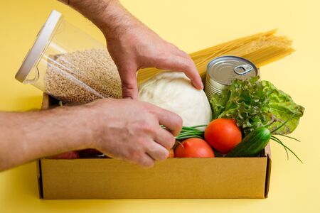 various food in a cardboard box and a donation sign on a yellow background, the concept of donation.の写真素材