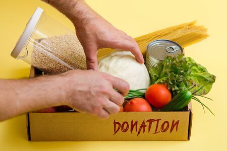 various food in a cardboard box and a donation sign on a yellow background, the concept of donation.の写真素材