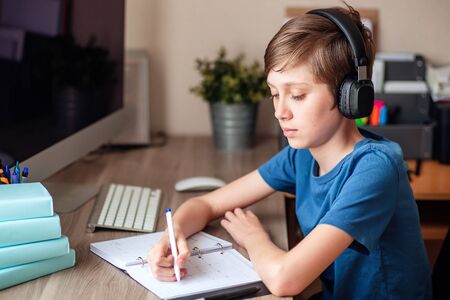 A teenage boy does homework, learns using a computer. Distance learning online. A child in...