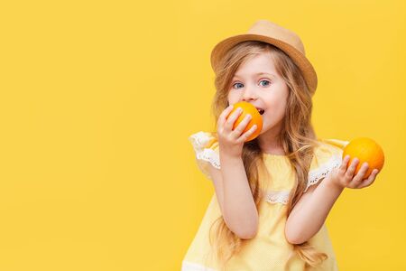 A little blonde girl with long hair with oranges in her hands.の写真素材
