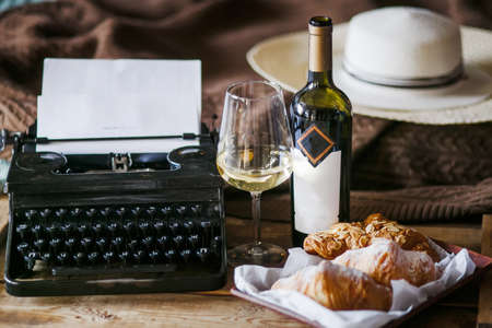 The inspiration of a writer typing texts on a vintage typewriter. Freelancer Breakfast croissants and wine. Office in the loft styleの写真素材