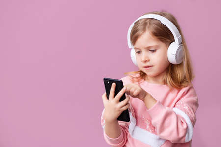 Little girl blogger influencer records videos from the blog on a smartphone, communicates with...