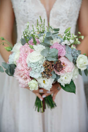 Beautiful delicate wedding bouquet in the hands of the brideの写真素材