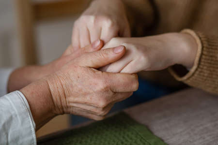 Close-up caring mature mother touches the hand of adult daughter, comforts and soothes, expresses...