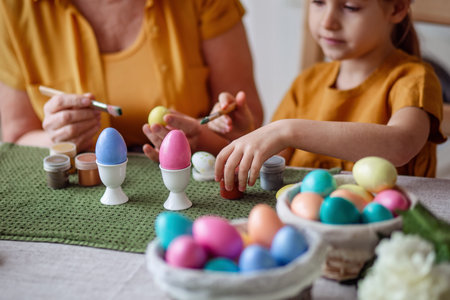 Happy easter family elderly grandmother and little granddaughter with rabbit ears are preparing for the holiday to paint eggsの写真素材