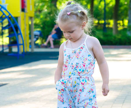A girl in the summer in the park walks on the playgroundの写真素材