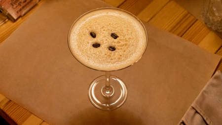 a cocktail with coffee beans in a glass glass is on the table