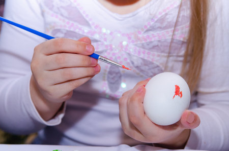 A little girl paints chicken eggs with a brush. The religious Orthodox holiday of Easter. Preparing for the holiday.の写真素材