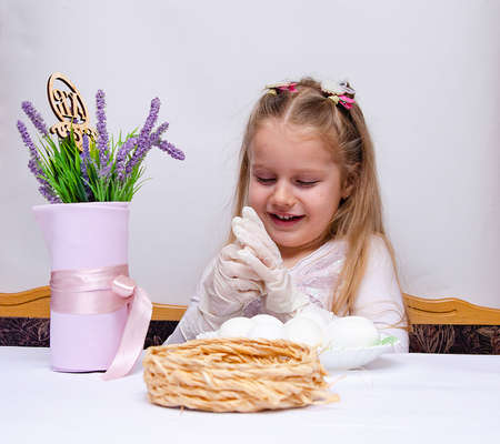 A little girl paints chicken eggs with a brush. The religious Orthodox holiday of Easter. Preparing for the holiday.の写真素材