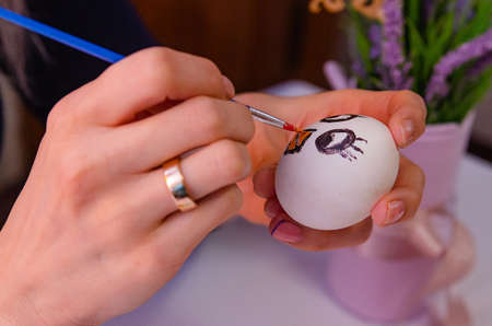 A girl paints chicken eggs with a brush. The religious Orthodox holiday of Easter. Preparing for the holiday.の写真素材