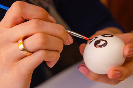 A girl paints chicken eggs with a brush. The religious Orthodox holiday of Easter. Preparing for the holiday.の写真素材
