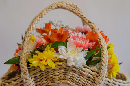 Wicker basket with flowers on a light colored backgroundの写真素材