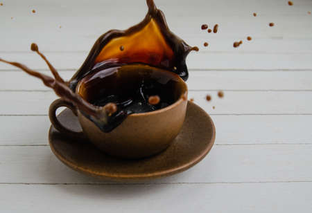 Black coffee with drops in a brown cup and saucer on a white background.の写真素材