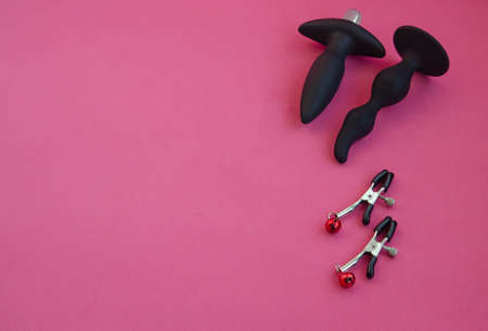 Toys for sex. Nipple clamps and anal dildos on a pink background.の写真素材