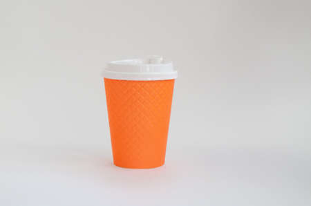 Orange paper cup with a white lid for coffee isolated on a white backgroundの写真素材