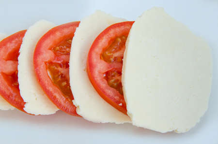 Vegetables tomatoes cut into rings and homemade salted cheese on a white background. Healthy food.