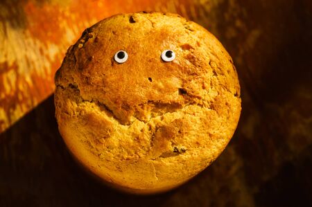 Close up of homemade fresh crusty bread on wooden rustic background with eyes and a smile shaped...