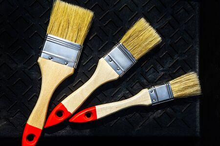 Three new brushes lay in a black roller tray ready for work DIYの写真素材