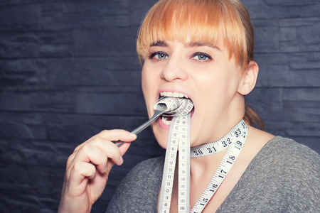 Woman on diet eating measuring tape instead of food, eating disorder and diet concept