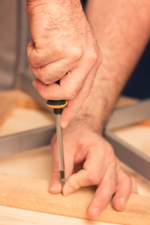 Male carpenter working on a DIY project, holding screwdriver in his handsの写真素材