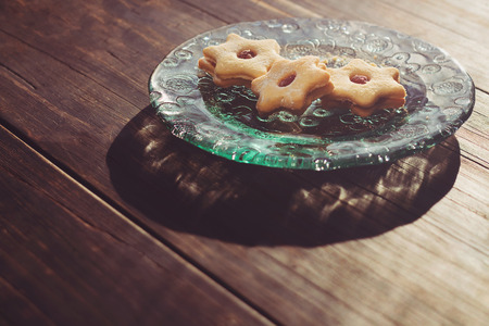 Jam filled cookies on a glass plate on wooden table in the morning lightの写真素材