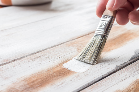 Hand holding paint brush and painting wooden boardsの写真素材