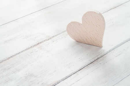 Wooden heart in morning light on white wooden boardsの写真素材