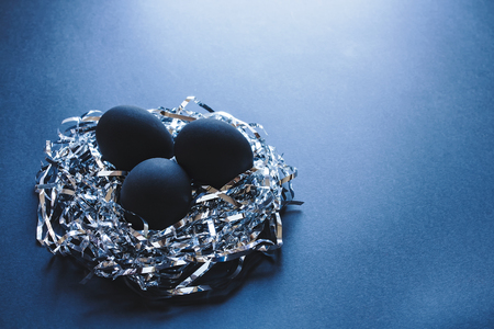 Three black eggs in a nest made of silver strings, on  a dark blue background, Easter conceptの写真素材