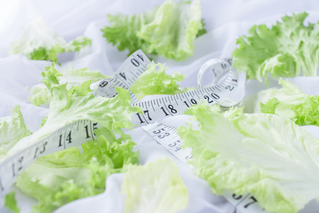 Lettuce leaves on white sheets with tape measure swirling aroundの写真素材