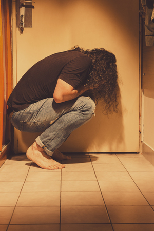 Man crouching on a floor tiles, sad, depressed and lonely, cryingの写真素材