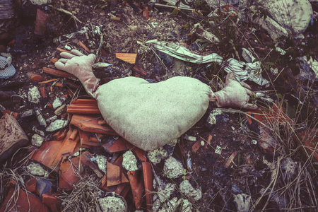 Discarded heart shaped decorative pillow in a pile of garbageの写真素材