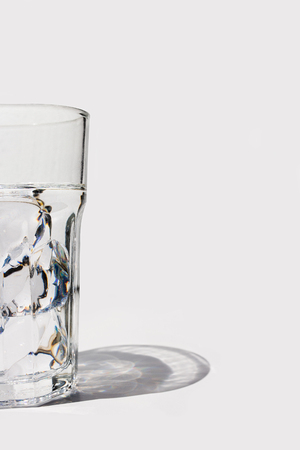 Fresh looking glass of water with ice cubes, on white background with shadowの写真素材