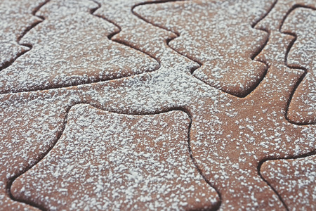 Gingerbread dough, rolled out with different Christmas shapes cut into it and sprinkled with...