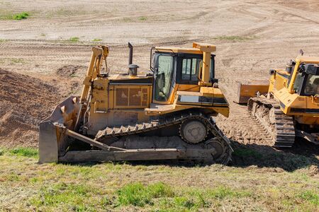 Yellow dozer on a dirt terrain with small patches of green grass
