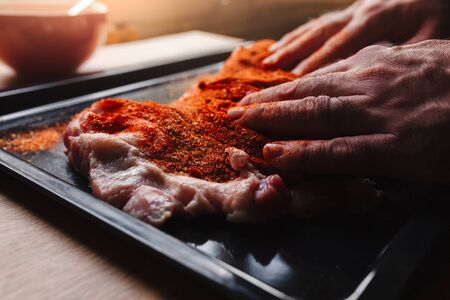 Man preparing raw piece of meat, rubbing different spices and herbs in it before roastingの写真素材