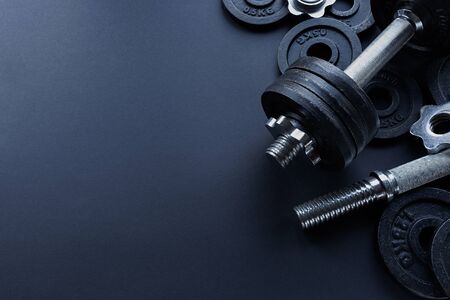 Free metal weights and weight plates on a dark gym floor