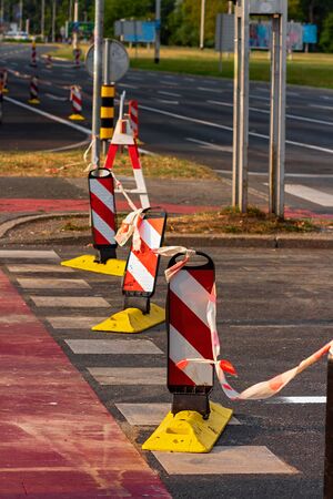 Closed of big city intersection, white and red striped plastic pillars blocking traffic on a pedestrian crossingの写真素材