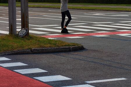 City intersection with pedestrian crossings and red bike lanes with just one lonely figure in the distance crossing roadの写真素材