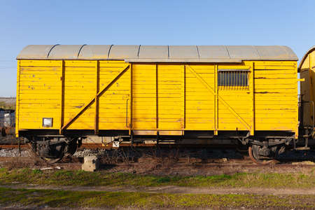 Old yellow cargo train wagon, grungy and weathered on the abandoned train tracks in fieldの写真素材